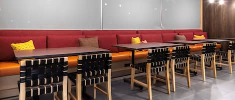 A modern restaurant with red cushioned seating, wooden tables, and black-and-white striped chairs.