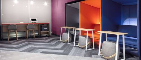 A modern office space with a desk area, two chairs, a small table, and a partition with a colorful interior.