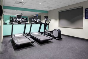 A fitness room with treadmills, a stationary bike, and a wall-mounted screen.