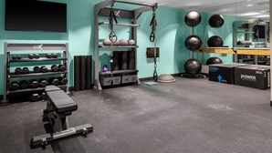 Un gimnasio con equipo de levantamiento de pesas, una banca y pelotas de ejercicio.