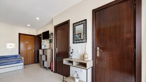 A hallway with a sofa, a console table with a vase, and a mirror on the wall. - Holiday Apartment “Da Praia” with Air Conditioning, Balcony, Shared Garden & WiFi (Portimão)