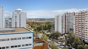 A high-rise building with multiple balconies, a flat roof, and a view of a cityscape. - Holiday Apartment “Da Praia” with Air Conditioning, Balcony, Shared Garden & WiFi (Portimão)