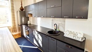 A modern kitchen with dark cabinets, a black countertop, and a sink with dish soap.