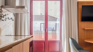 A modern kitchen with wooden cabinets, a marble countertop, and a red door leading to a balcony. - Uma Formosa Apartments (Porto)