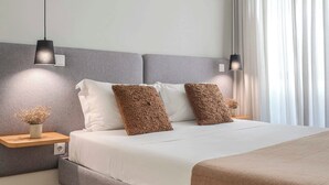 A modern hotel room with a large bed, bedside lamps, an air conditioning unit, and a view of the outdoors through sheer curtains. - Uma Formosa Apartments (Porto)