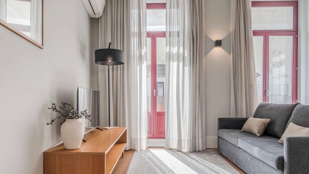 A modern living room with a grey sofa, a wooden side table, and a vase with dried flowers. - Uma Formosa Apartments (Porto)