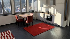Moderni keittiö, jossa on ruokailutila, suuret ikkunat ja punainen matto.