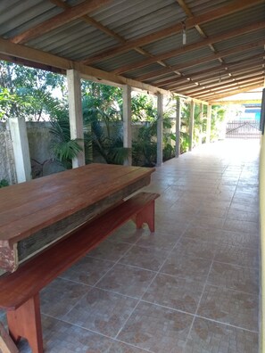 Relax in a serene garden courtyard with a long bench, surrounded by lush greenery and a metal gate.