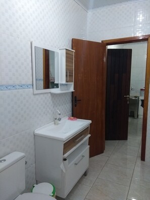 Compact bathroom with a sink, mirror, and tiled walls.