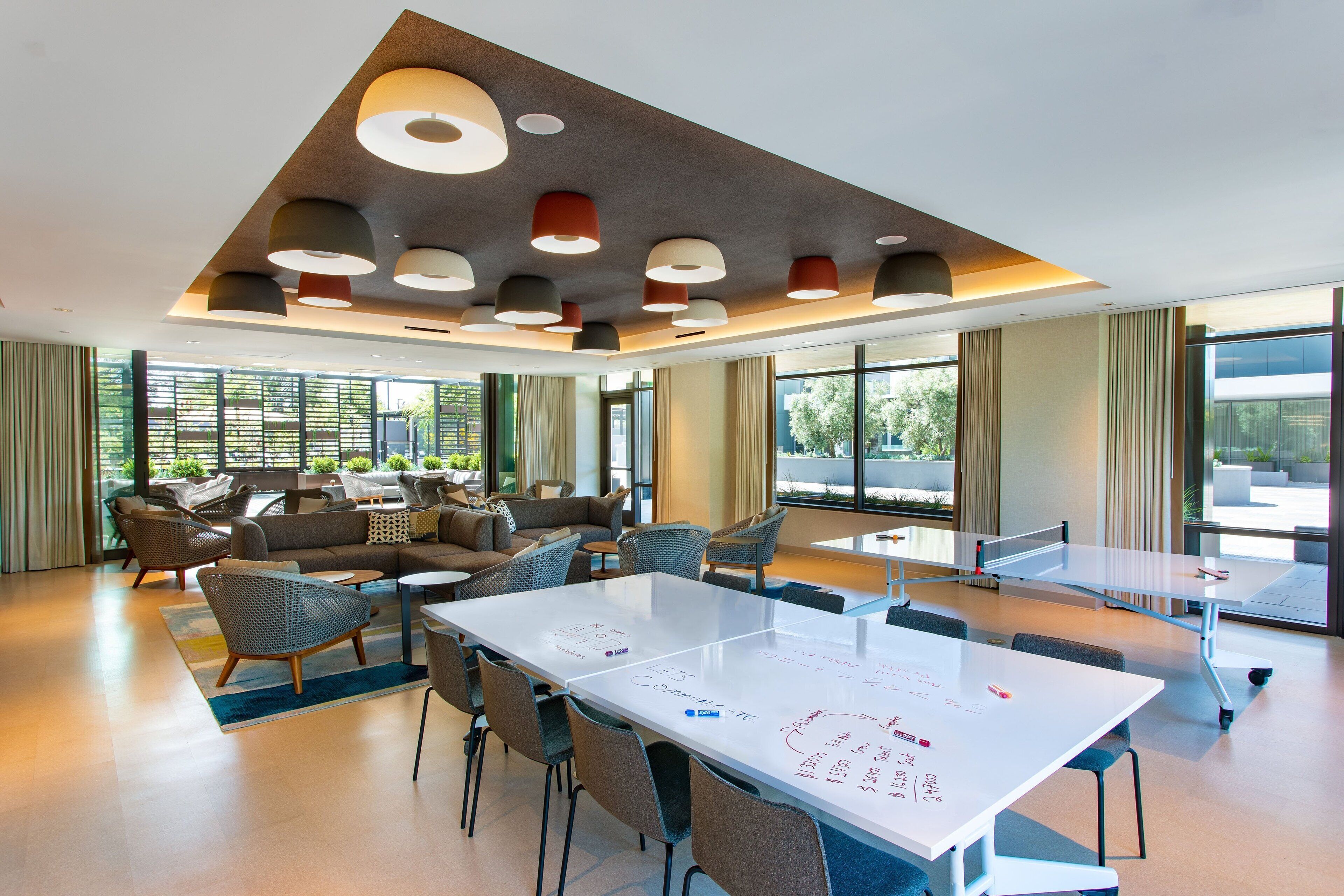Uma sala de conferências moderna com uma mesa branca grande, assentos confortáveis e janelas amplas que oferecem vista para o exterior.