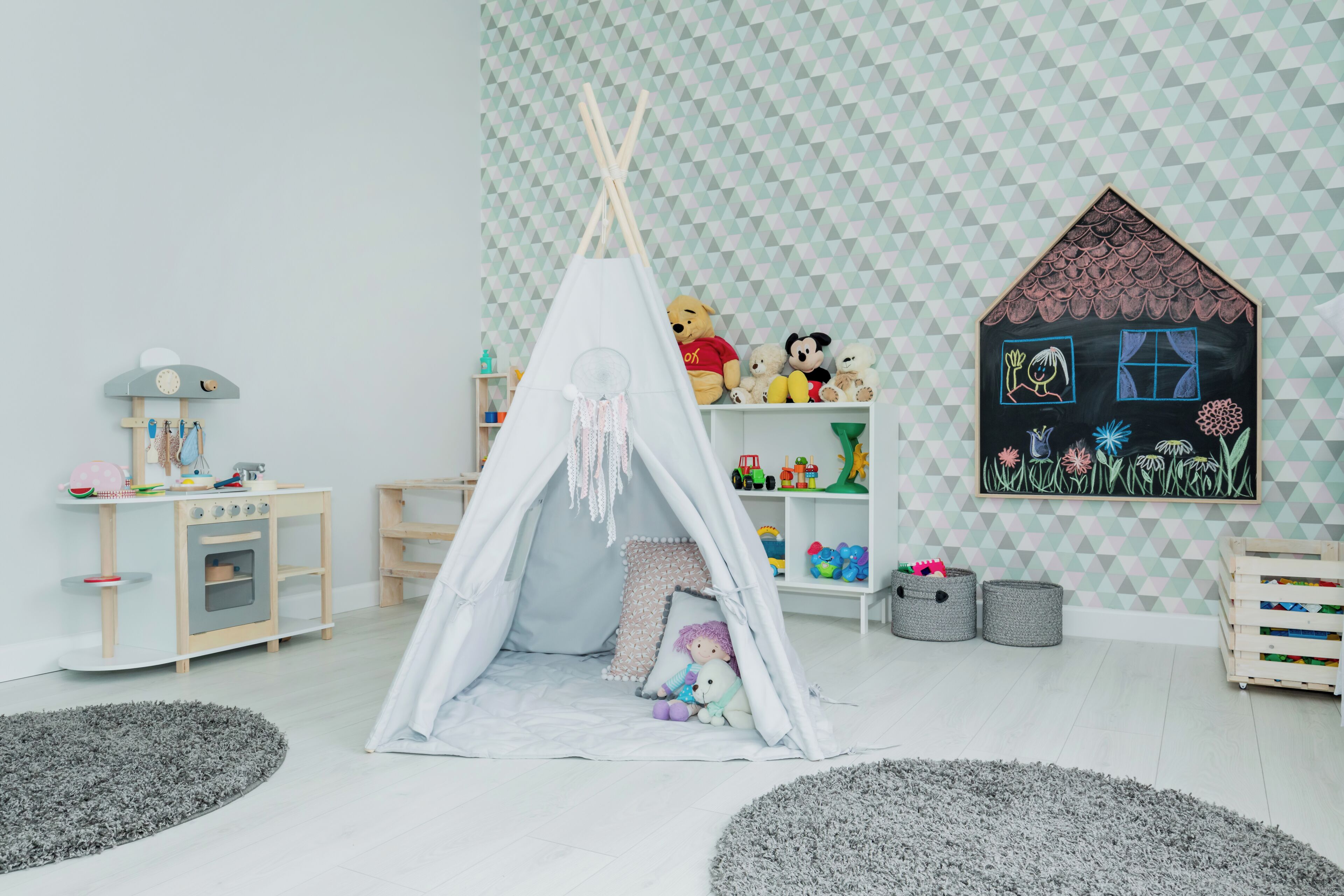 A playroom with a teepee, toys, and a wall painting.
