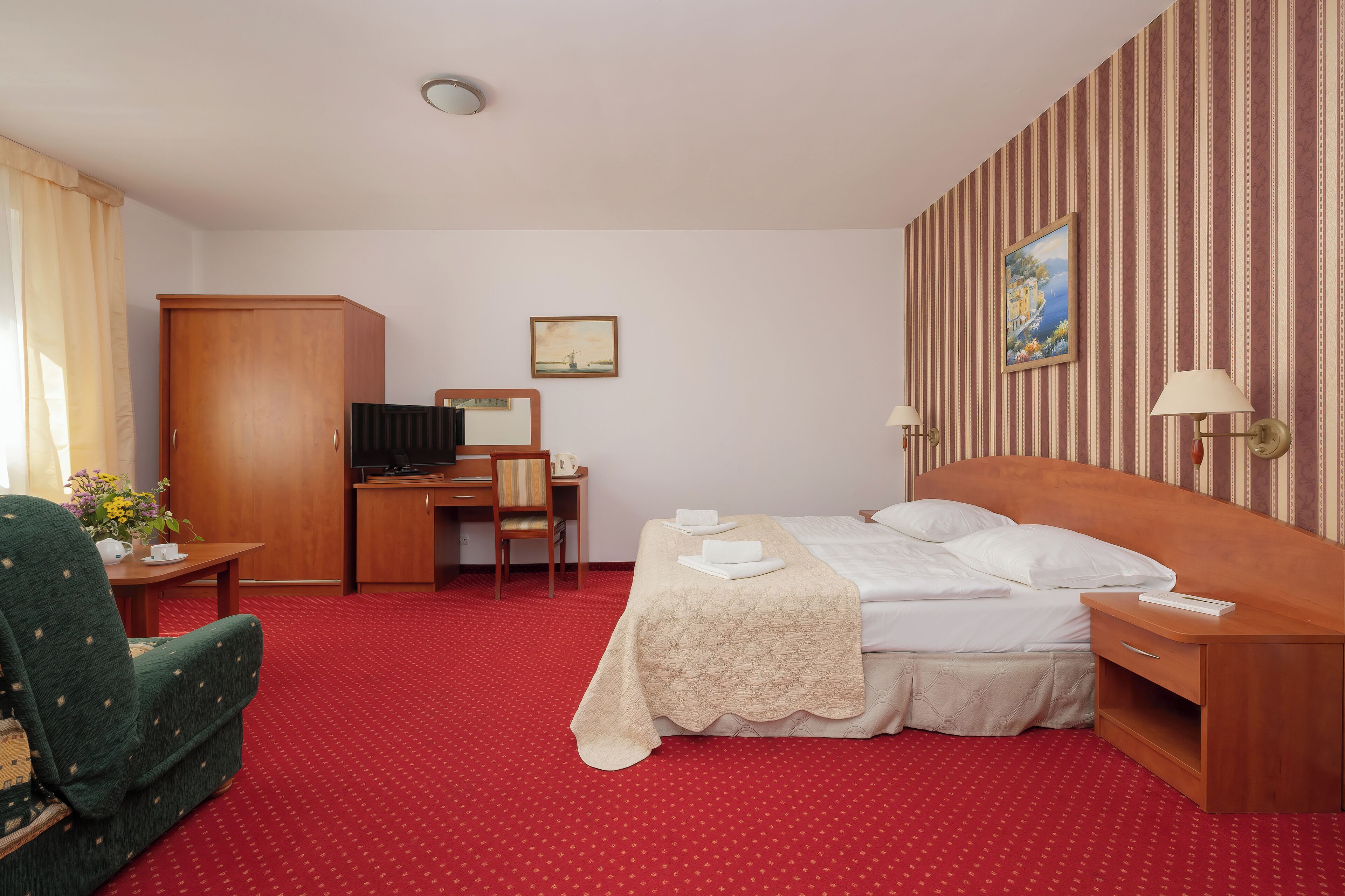 Una habitación de hotel con cama, escritorio, silla, armario y televisor.