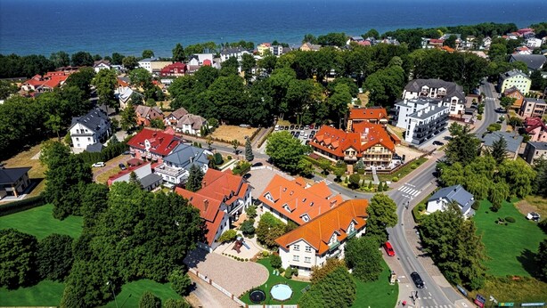 Vue aérienne d’un quartier résidentiel avec des maisons, une route et une étendue d’eau en arrière-plan.