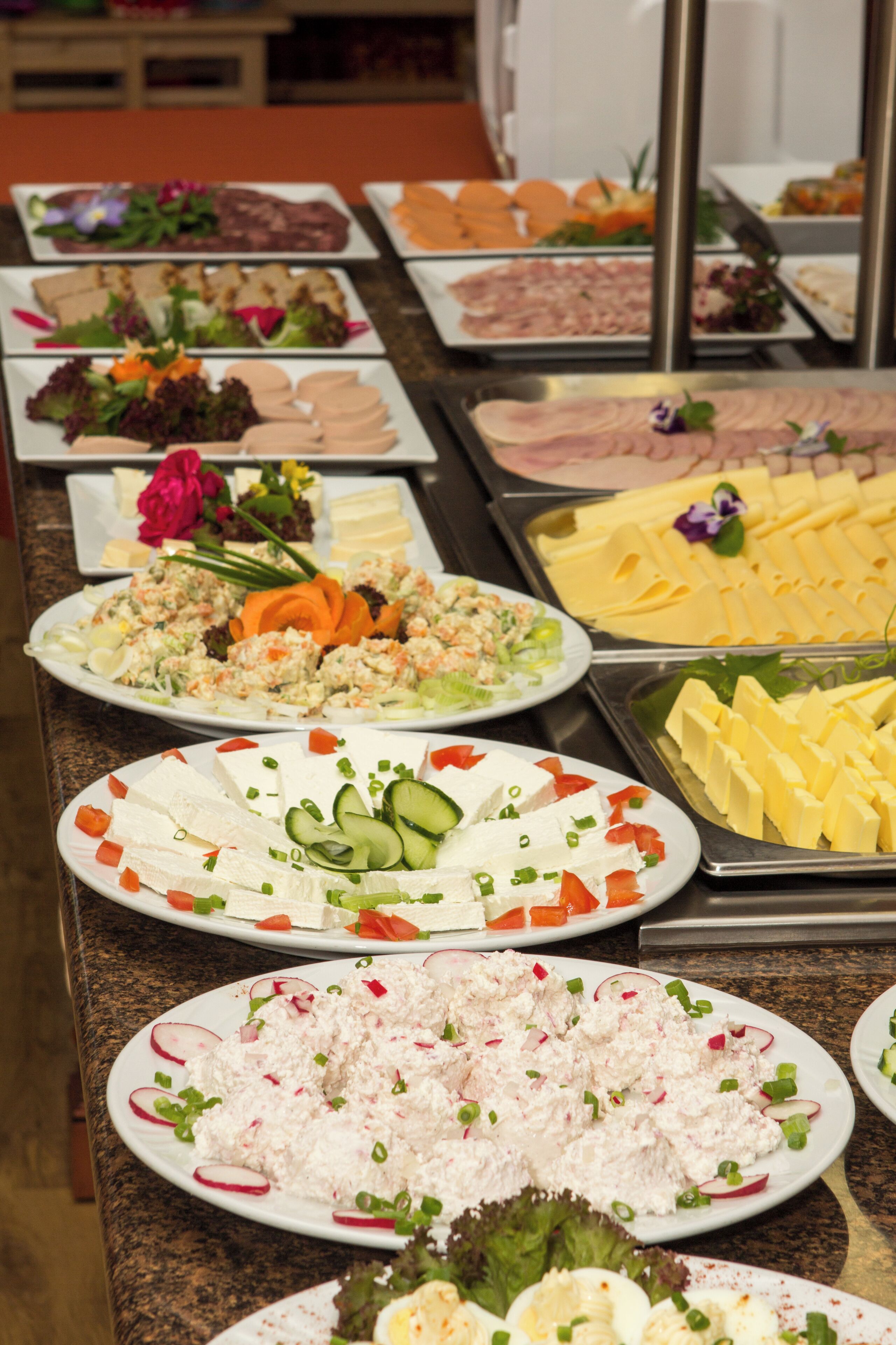Un buffet proposant une variété de plats, notamment des salades, des viandes, des fromages et d’autres mets.