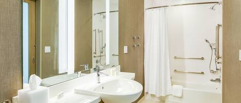 A modern bathroom with two sinks, a large mirror, a shower area with a glass door, and a bathtub.