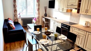 Eine moderne Küche mit Essbereich, mit einem Glastisch, Stühlen und einer Couch.