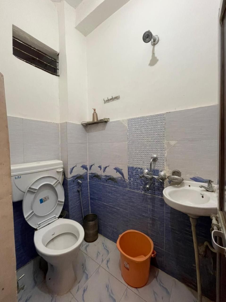 A bathroom with a toilet, sink, shower, and decorative wall tiles.