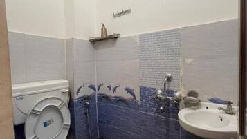 A bathroom with a toilet, sink, shower, and decorative wall tiles.
