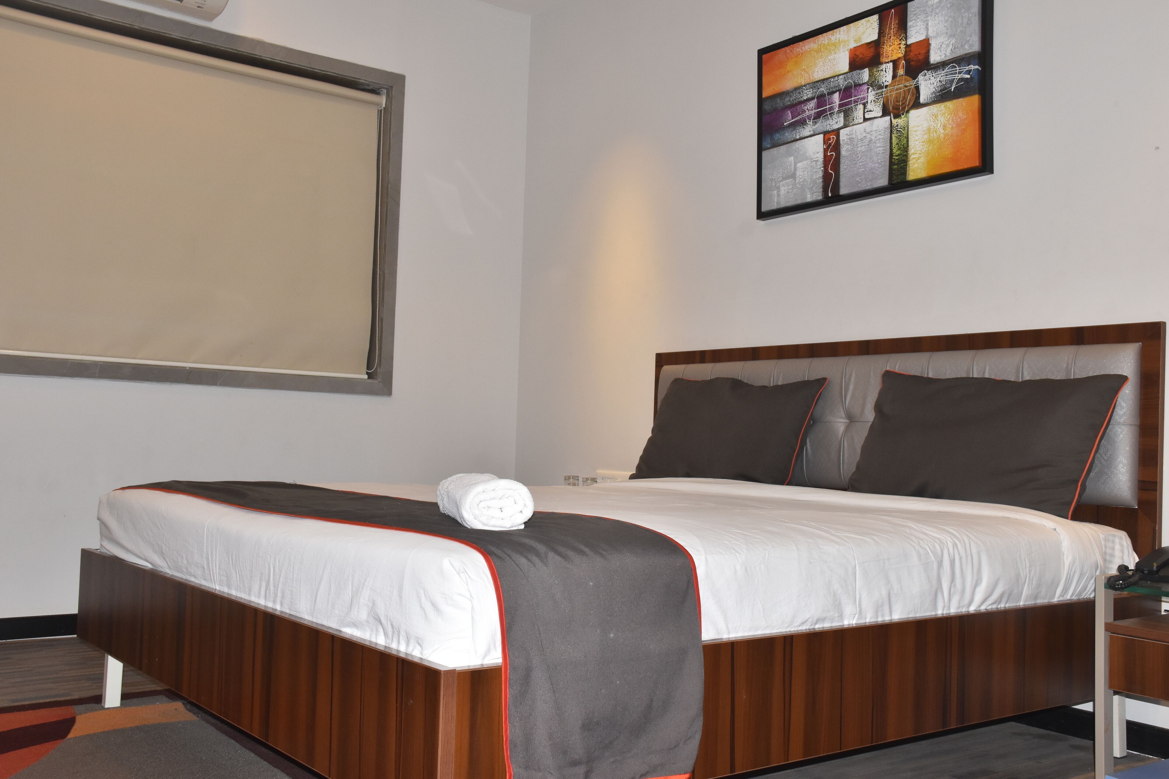 A neatly made bed with a white and gray bedspread, a wooden headboard, and a single pillow.