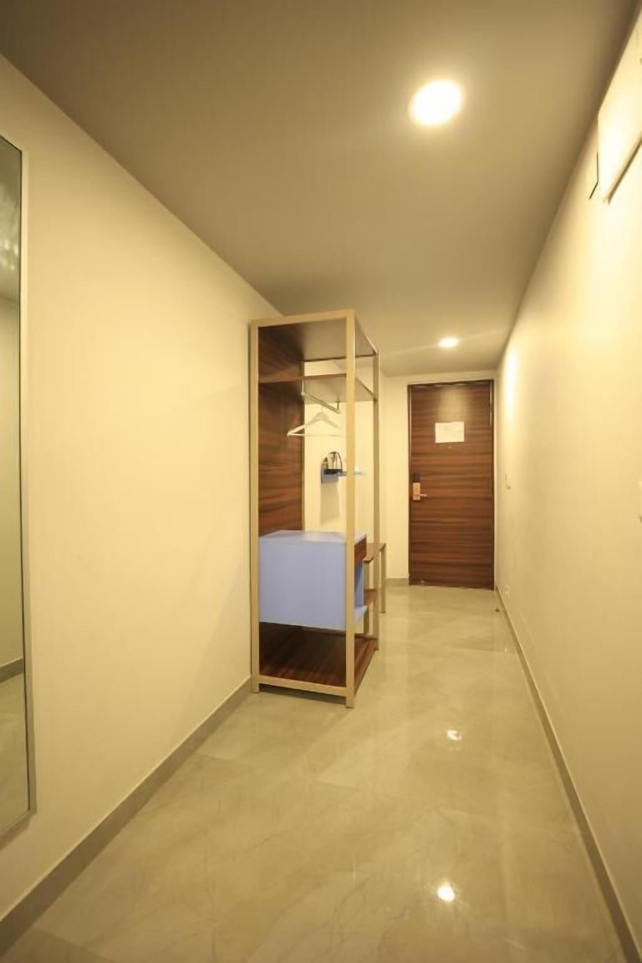 A hallway with a bed, a wooden door, and a mirror on the left wall.