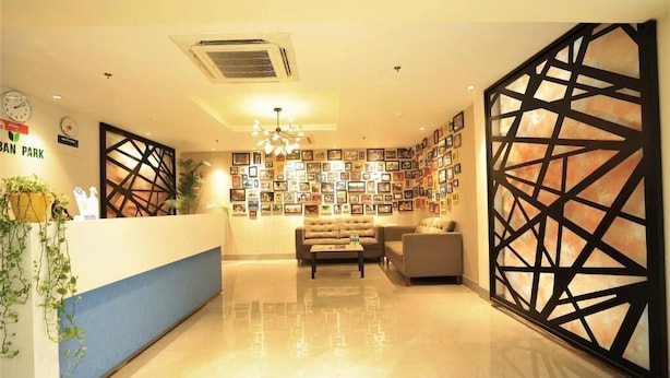 Zona de recepción de un hotel con un mostrador azul, un sofá y una pared decorada con cuadros.