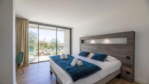Een moderne slaapkamer met een groot bed, een houten hoofdbord en een schuifdeur van glas naar een buitenruimte.
