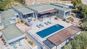 Een modern huis met een zwembad, een terras van natuursteen en een buiten zitgedeelte.