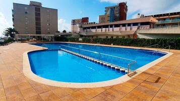 A swimming pool with a tiled deck, surrounded by buildings.