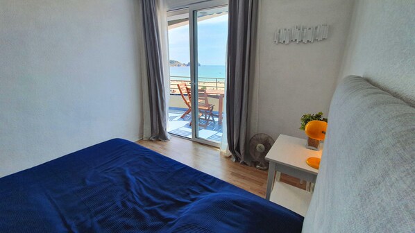 A bedroom with a large bed, a small table with a fan, and a view of a balcony with a table and chairs. - Rocamaura II-6-9 Apartment to rent in L'Estartit. First line on sea and the beach (Estartit)