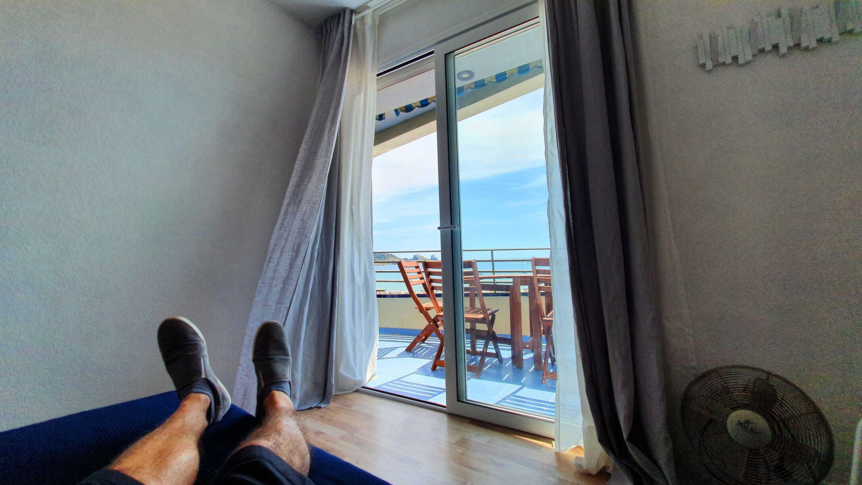 A room with a view of a balcony, a fan, and a table with chairs.