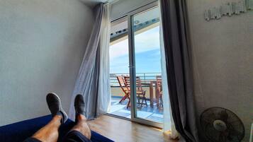 A room with a view of a balcony, a fan, and a table with chairs.