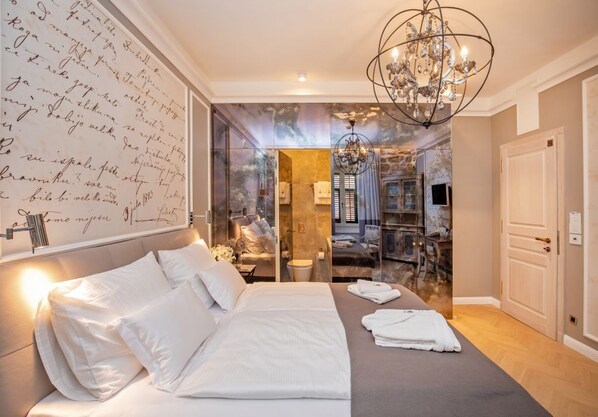 A hotel room with a large bed, a chandelier, and a wall with handwritten text.
