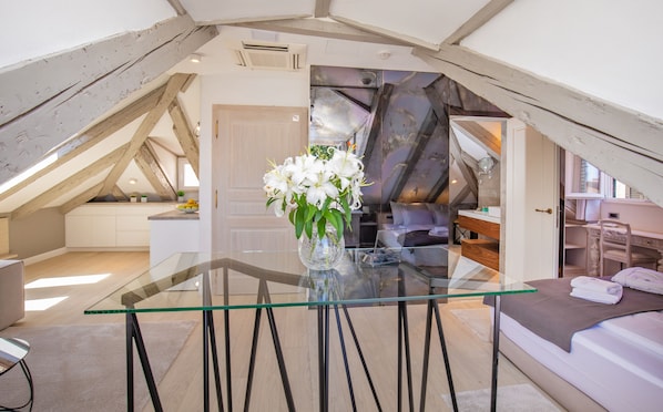 Une chambre de style loft moderne, avec une table à manger en verre, un canapé et une vue sur la cuisine et l’espace de vie.