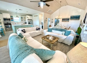 A spacious living area with a large sofa, a coffee table, and a dining area with a chandelier. - READER'S RETREAT - Close to the beach, great outdoor space with bar (Crystal Beach)