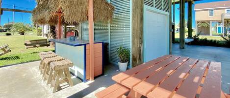 Un patio al aire libre con bancos de madera y una estructura de techo de paja.