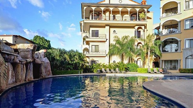A hotel with a swimming pool, a rock feature, and a well-maintained garden. - Stay in Tamarindo Condominiums (Tamarindo)