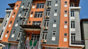 Un edificio de varios pisos con un diseño arquitectónico moderno, que cuenta con balcones y unidades de aire acondicionado.
