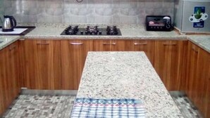 Una cocina con armarios de madera, estufa a gas, microondas y un tapete estampado.