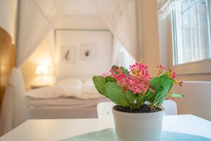 A room with a bed, a bedside table with a lamp, and a window with curtains.