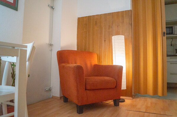A room with a wooden door, a white chair, and a wooden floor.