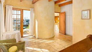 Una habitación con una mesa, una silla de mimbre y vistas al exterior por un ventanal.