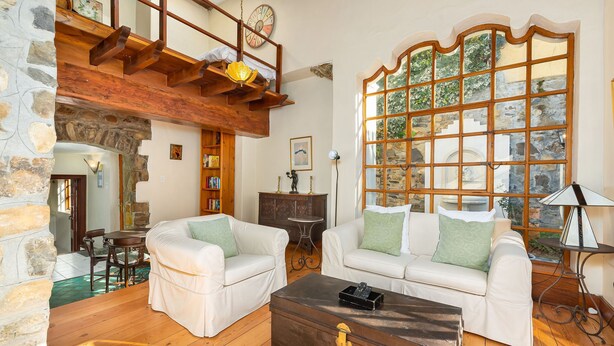 Una sala de estar acogedora con dos sofás blancos, una mesa de centro de madera y una pared de piedra.