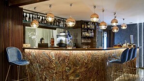 Un espace bar doté d’un comptoir en marbre, de tabourets de bar bleus et de luminaires suspendus.