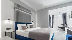 Une chambre d’hôtel moderne, dotée d’un grand lit, de tables de chevet, d’un bureau et d’une chaise.