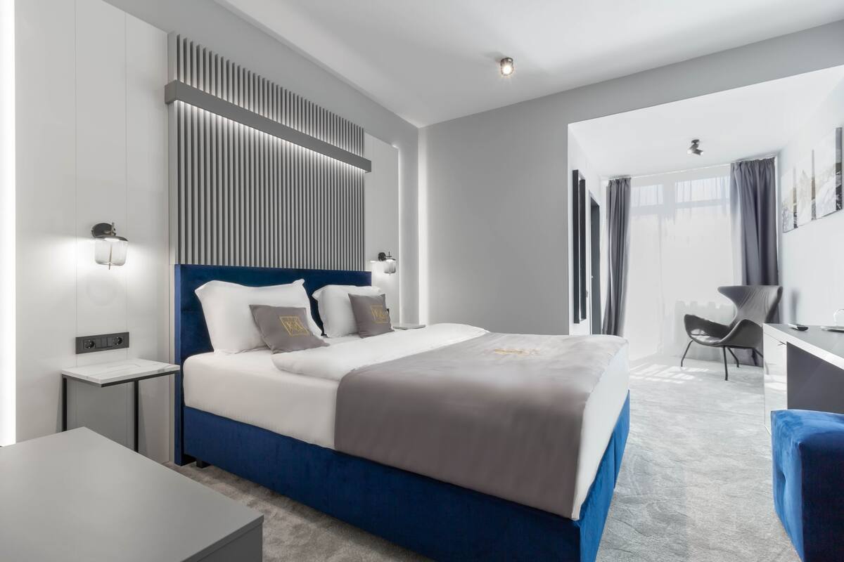A modern hotel room with a large bed, bedside tables, a desk, and a chair.