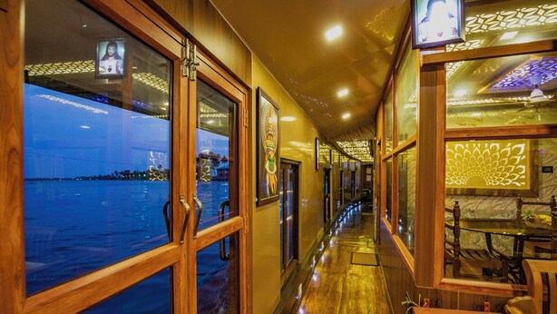 Un pasillo con suelo de madera y amplias ventanas con vistas al agua.