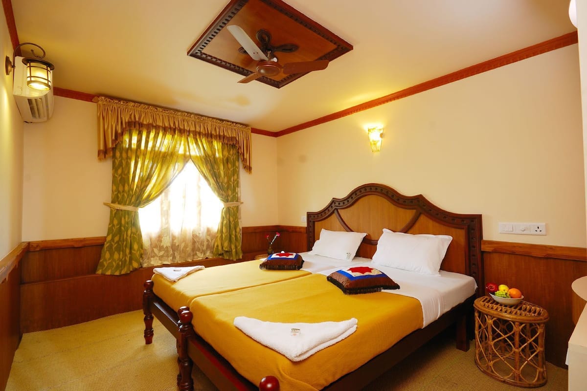 A double bed with a wooden headboard, a bedside table with fruit, and a ceiling fan.