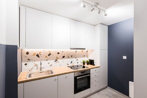Eine moderne Küche mit weißen Schränken, einer Holz Arbeitsplatte, einem eingebauten Backofen und einer Spritzschutzwand mit Punktmuster.