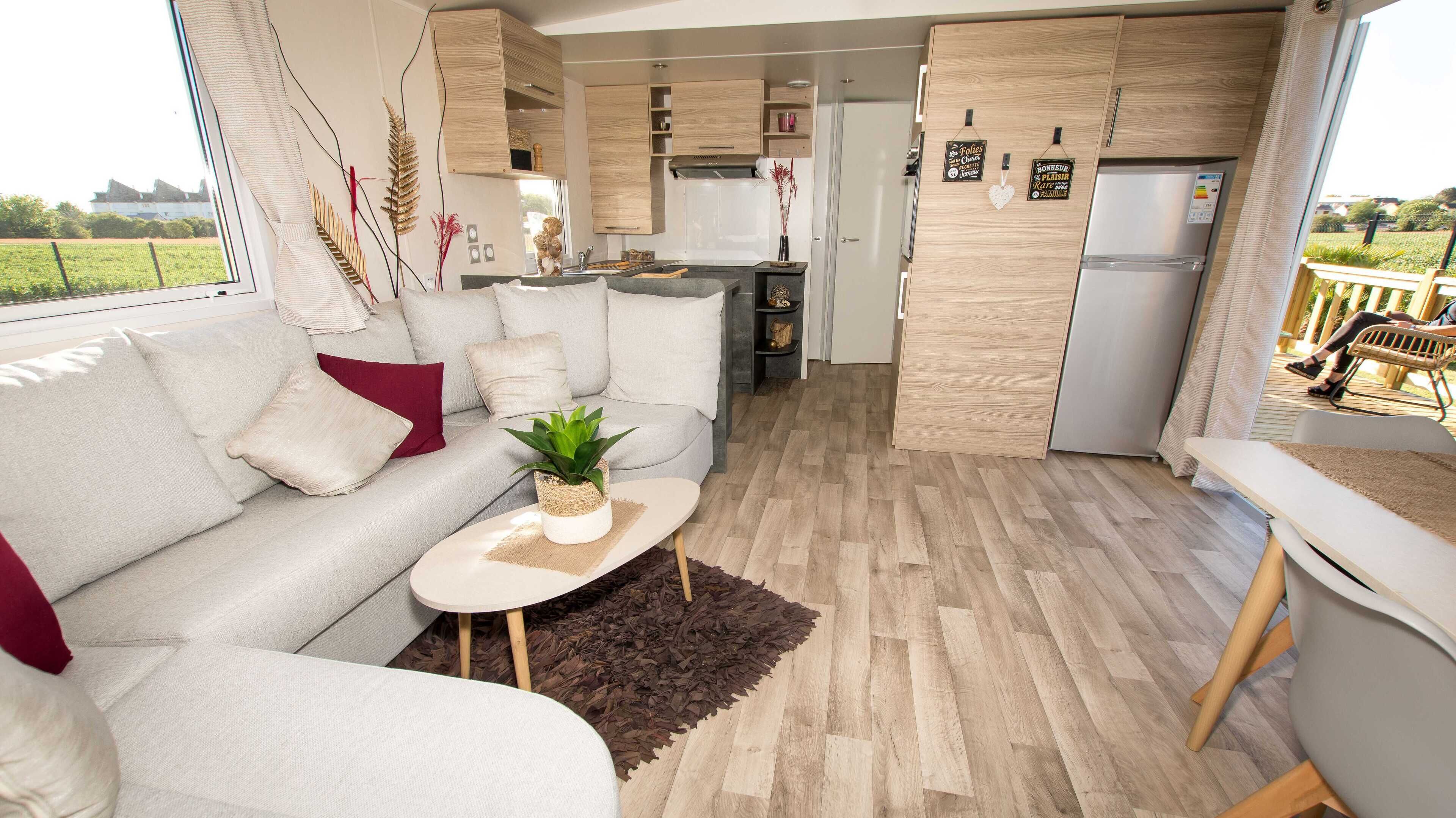 A modern living room with a sofa, coffee table, and a view of the kitchen and outdoor area.