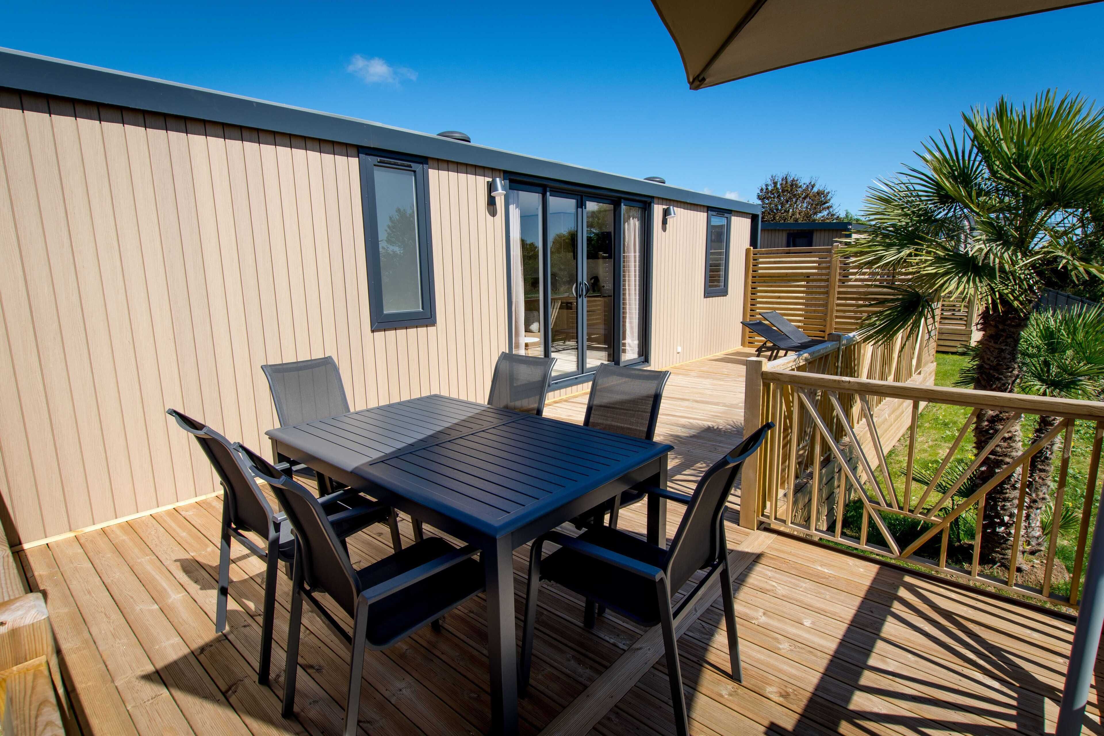 A deck with a table and chairs, a wooden fence, and a palm tree.